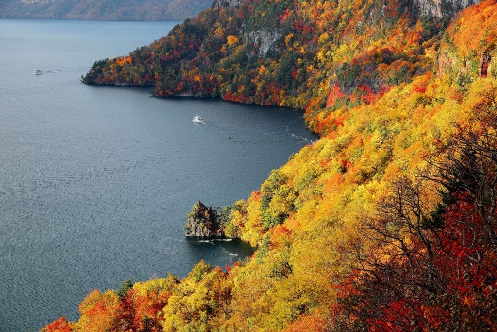 aerial-view-of-a-sightseeing-boat-on-autumn-lake-towada-in-towada-hachimantai-national-park-aomori-japan-56929182685