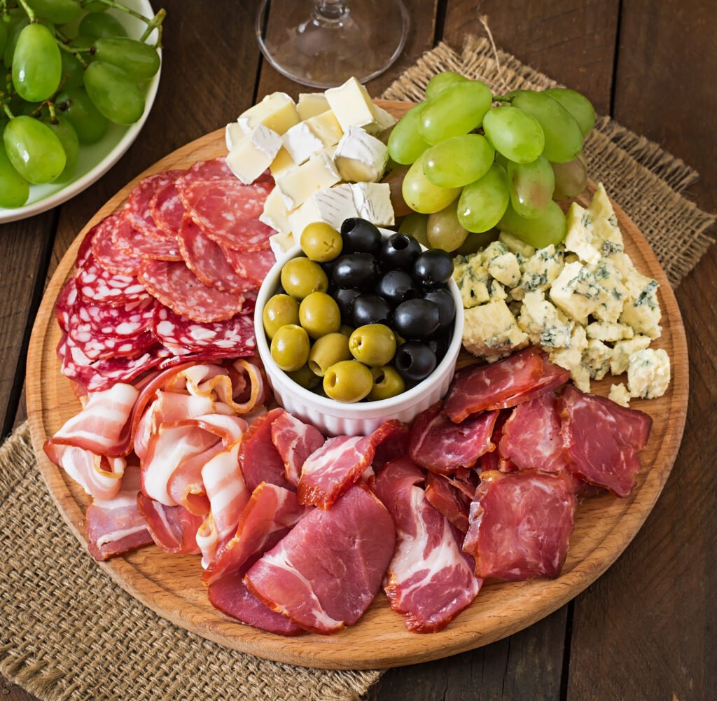 antipasto-catering-platter-with-bacon-jerky-salami-cheese-grapes-wooden-table