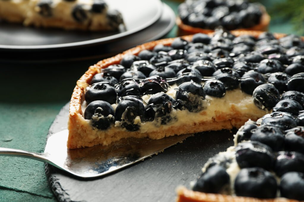 Concept of tasty lunch with blueberry pie on green background