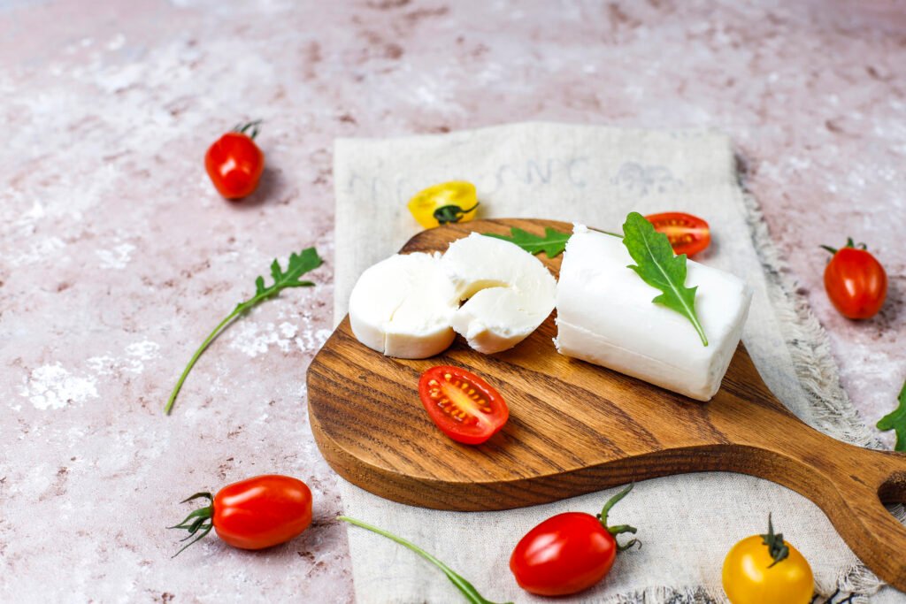Goat Cheese Slices on Wooden Board with ruccola,cherry tomatoes.