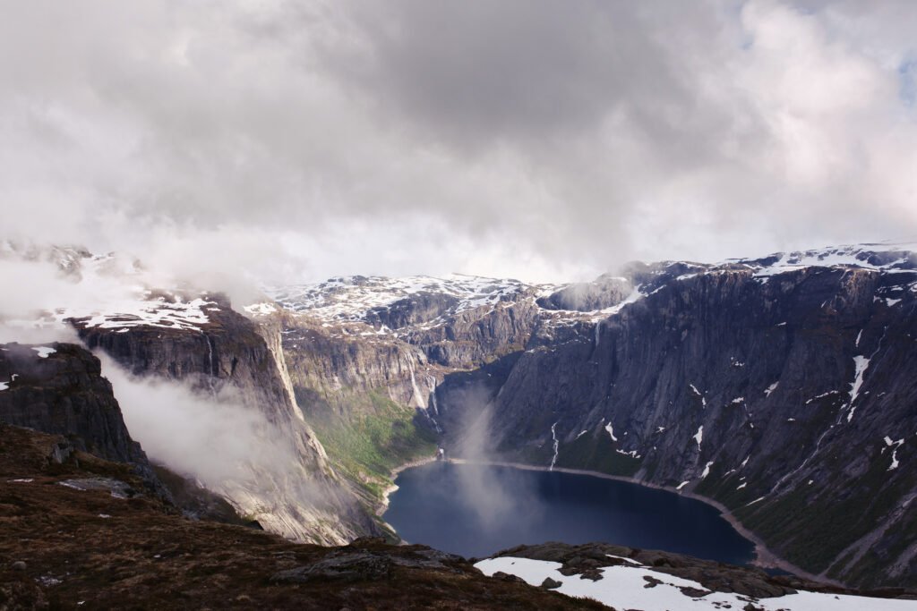Look from above at blue lake among tall rocks in the Norway