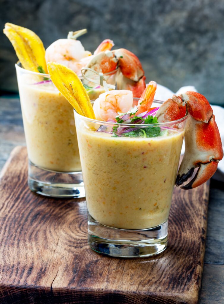 Peruvian seviche LECHE DE TIGRE. Tiger milk. Raw fish cocktail ceviche with lime, grinder, chili and cilantro. Traditional peruvian food decorated with crabs, srimps and banana chips