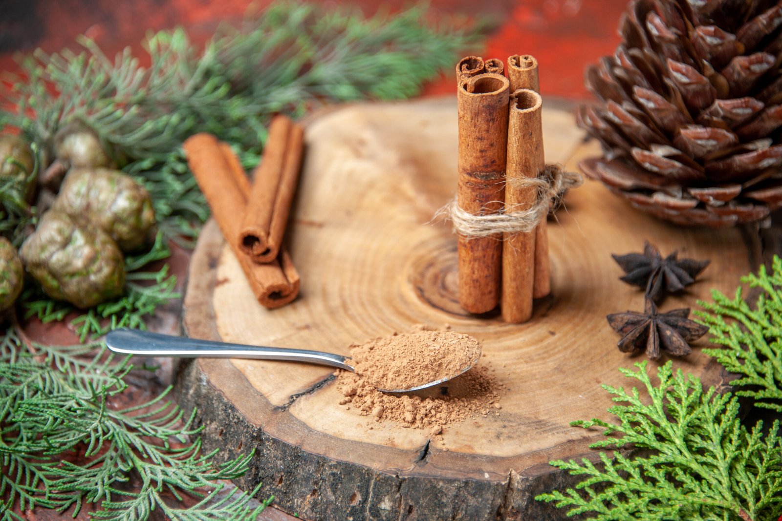 front-view-cinnamon-sticks-cinnamon-powders-pinecone-anises-wood-board-spoon-with-cinnamon-powder-dark