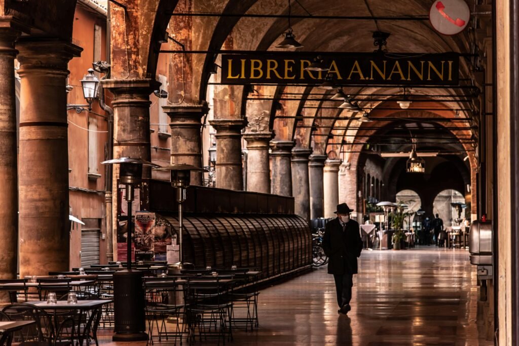 A man walks under the arches of Bologna's historic portico, Italy.