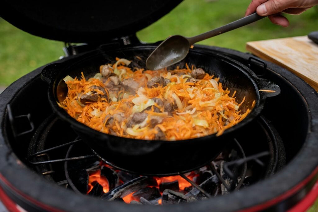 Delicious beef with vegetables sizzling in a cast iron skillet over an open flame, outdoor cooking style.