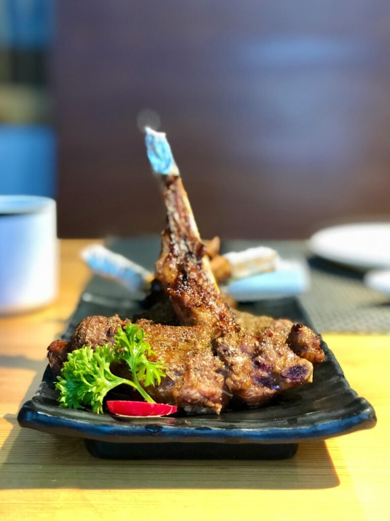 pexels-photo-2871755-2871755 Delicious grilled lamb chops served with fresh garnishes on a black plate.
