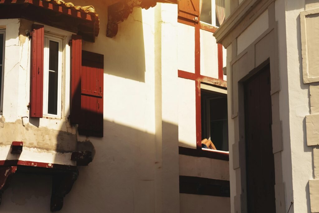 A picturesque view of Basque architecture in Saint-Jean-de-Luz with red shutters and soft sunlight.