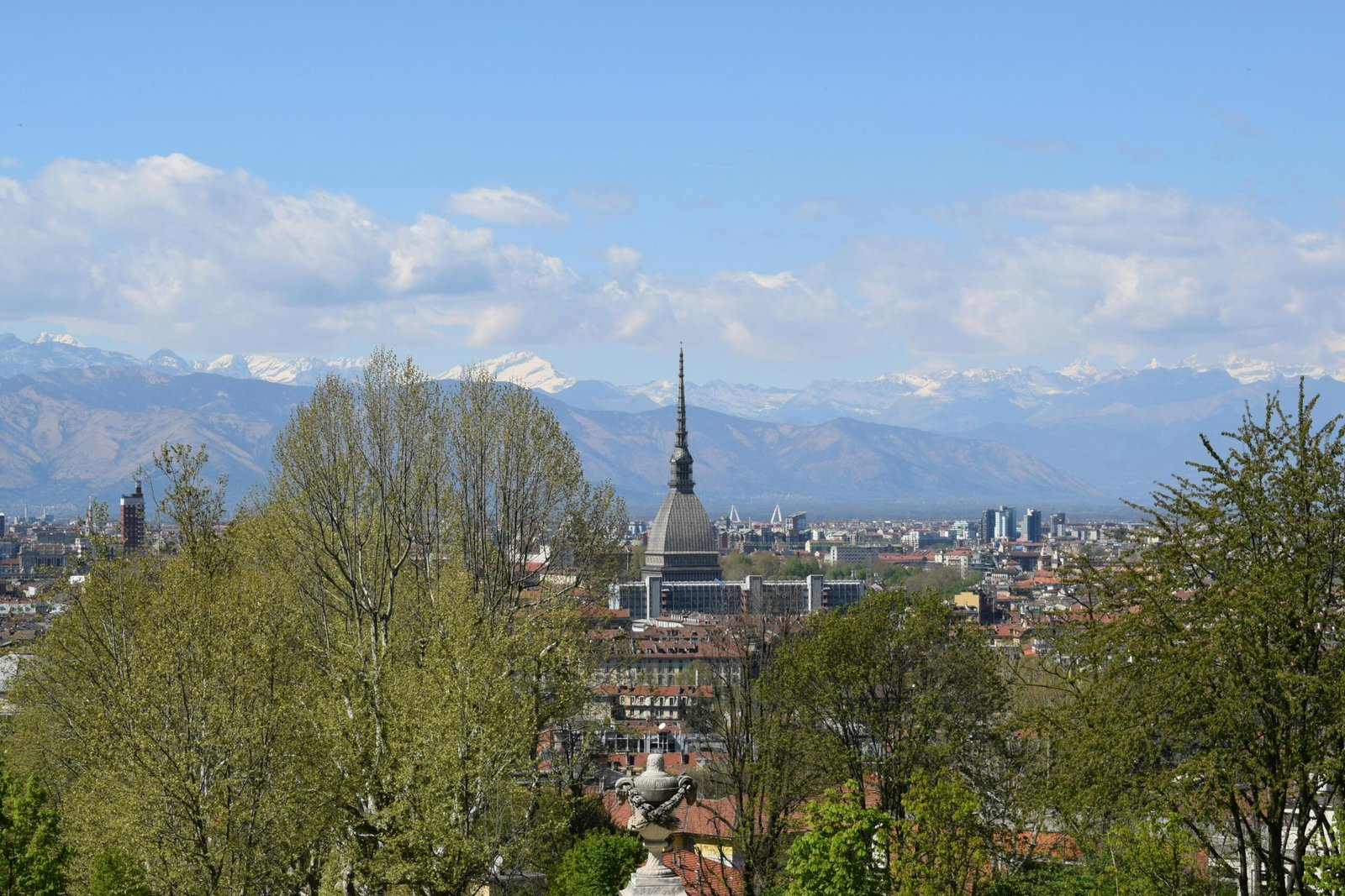 Panoramic view of Turin, Italy, showcasing La Mole Antonelliana and the Alps under a clear blue sky.